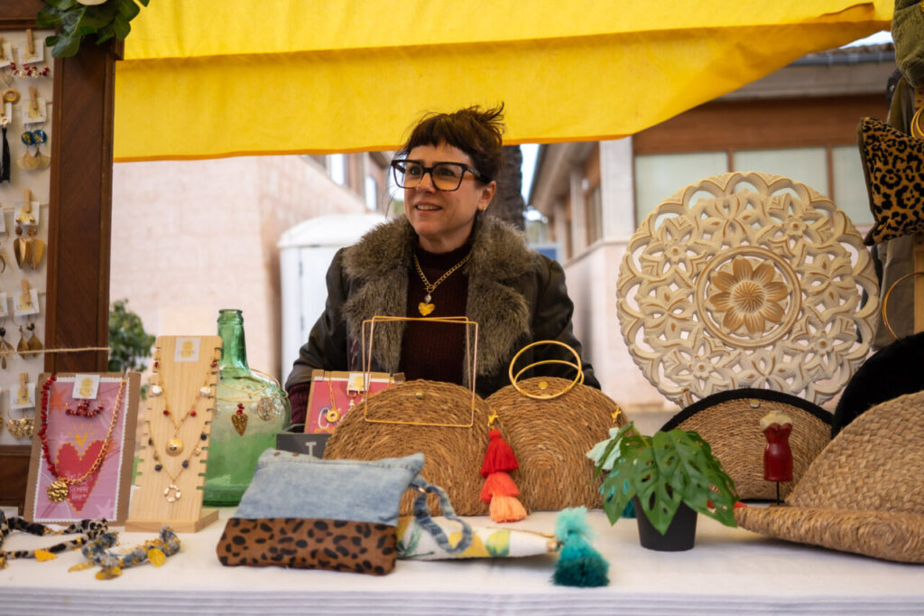Mujer sonriente en un mercado de artesanías con joyería y accesorios