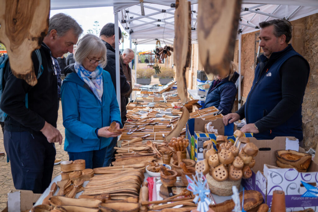 Personas explorando un mercado de artesanía en Fira de Andratx