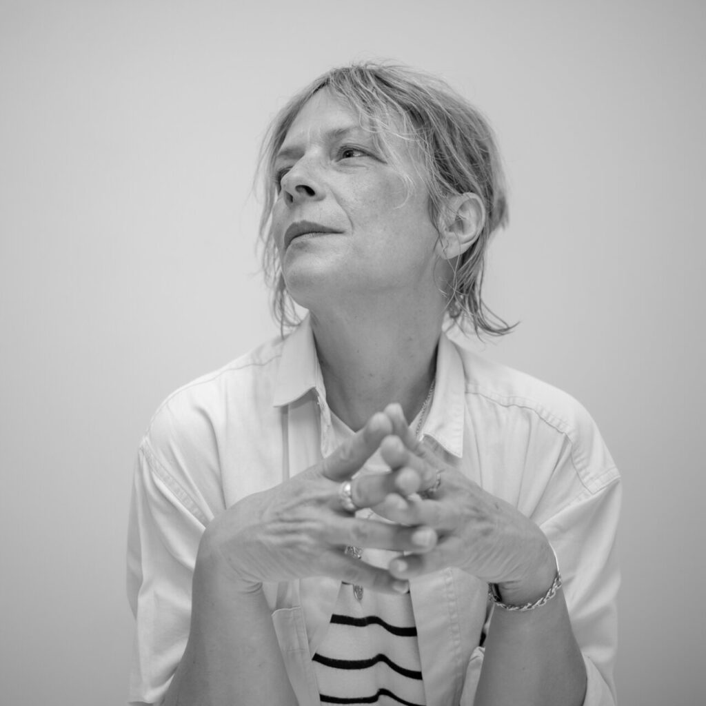 Retrato en blanco y negro de una mujer pensativa con las manos entrelazadas.