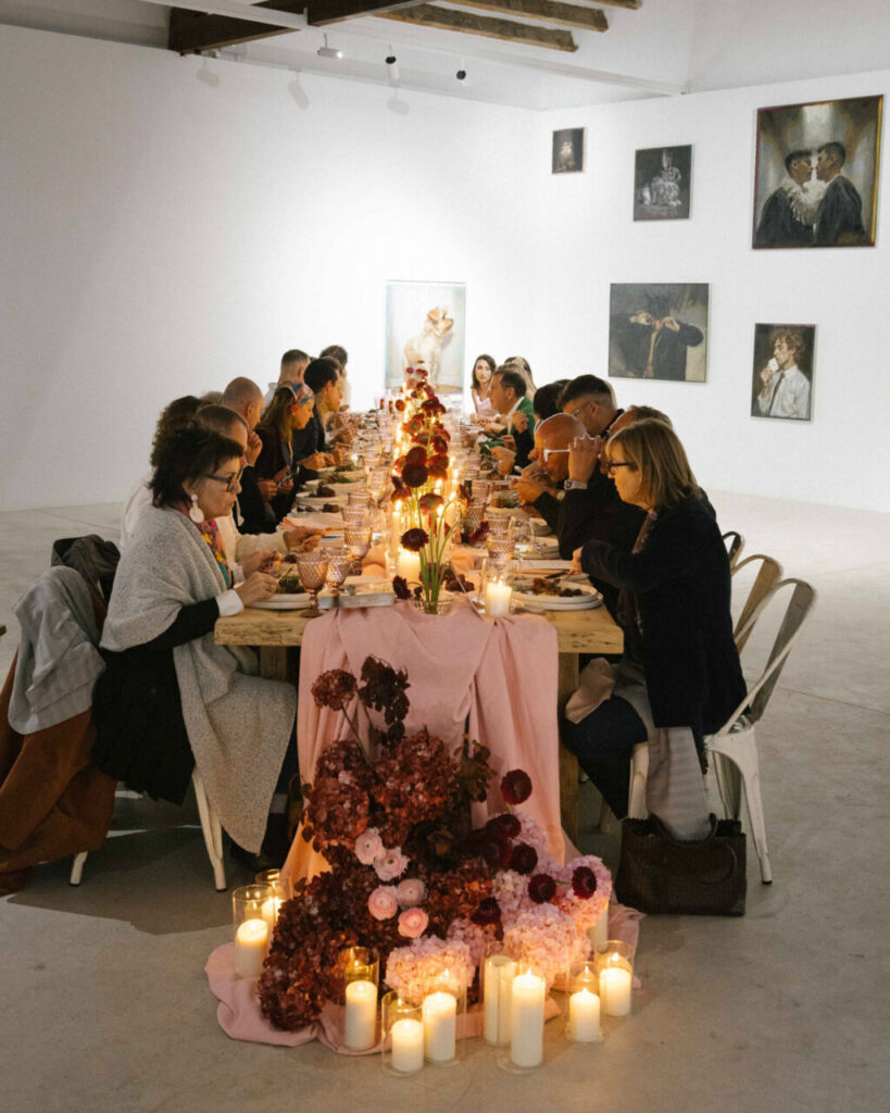 Mesa decorada con flores y velas durante una cena de moda y arte