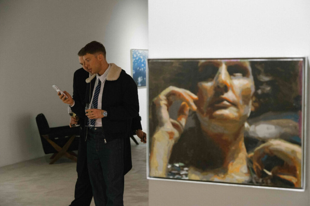 Dos hombres en un evento de moda observando una obra de arte