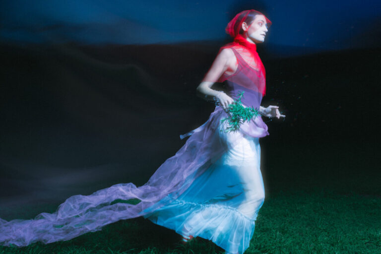 Artista con vestido tradicional y elementos contemporáneos en un entorno oscuro