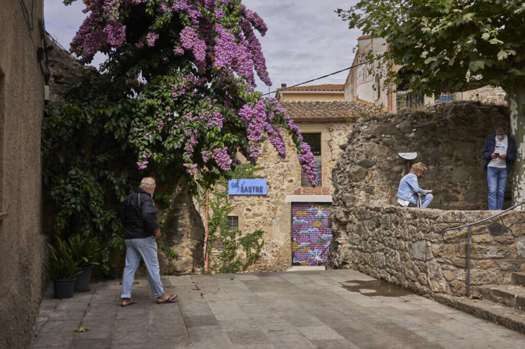 Peratallada: el pueblo medieval que detiene el tiempo en el Baix Empordà 9 Hombre caminando en un callejón con flores moradas