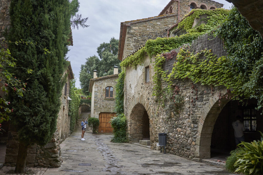 Peratallada: el pueblo medieval que detiene el tiempo en el Baix Empordà 1 Calle empedrada con casas de piedra y vegetación en los Pirineos Catalanes