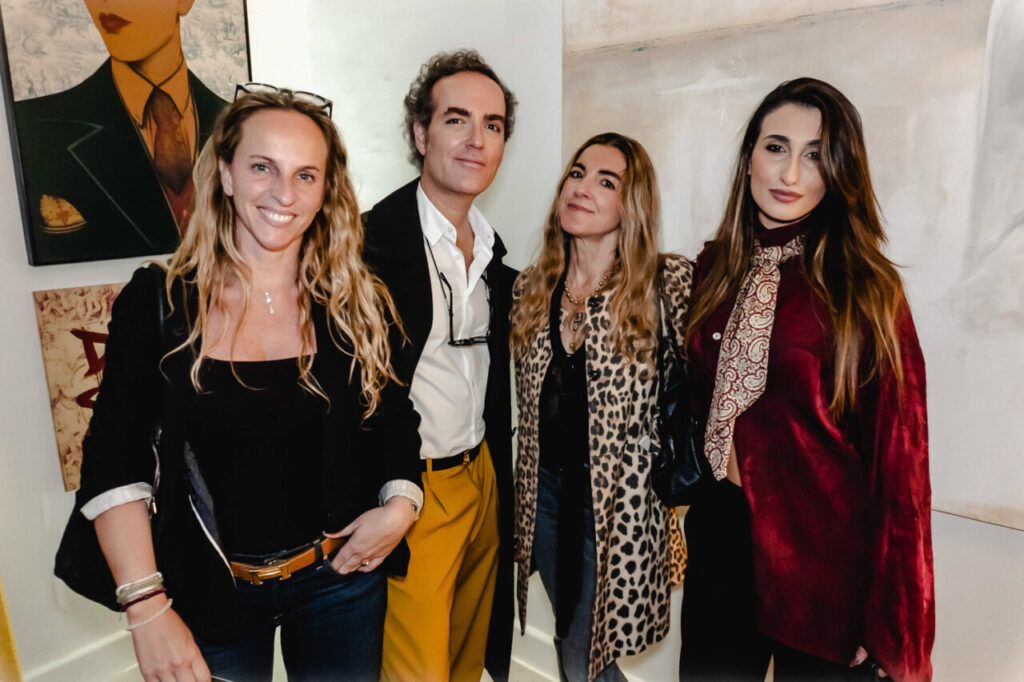 Cuatro personas posando en una galería de arte durante un evento privado.