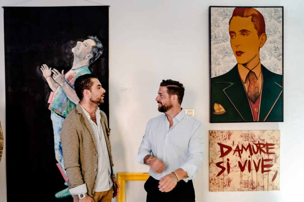 Dos hombres conversando frente a obras de arte en La Bibi Gallery.