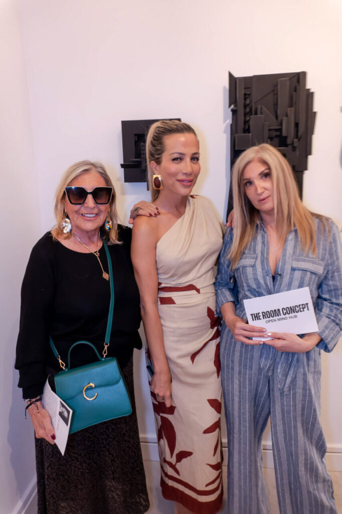 Tres mujeres posando en una galería de arte durante un evento