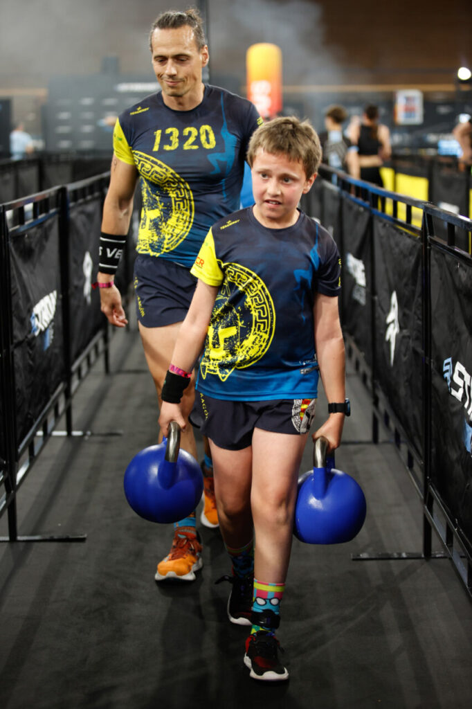 Atleta y niño compitiendo en la Strong Race 2026 con kettlebells