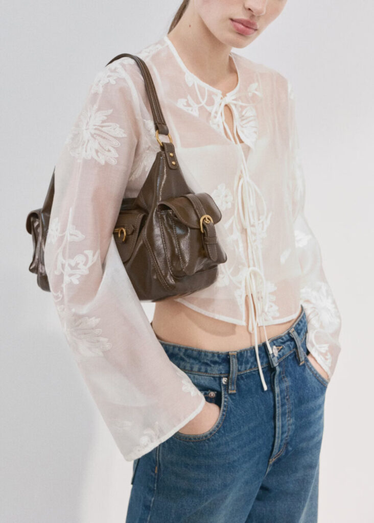 Transparencias y capas ligeras: la tendencia más seductora de la primavera-verano llega para quedarse 2 Modelo con blusa transparente y bolso marrón en un fondo claro