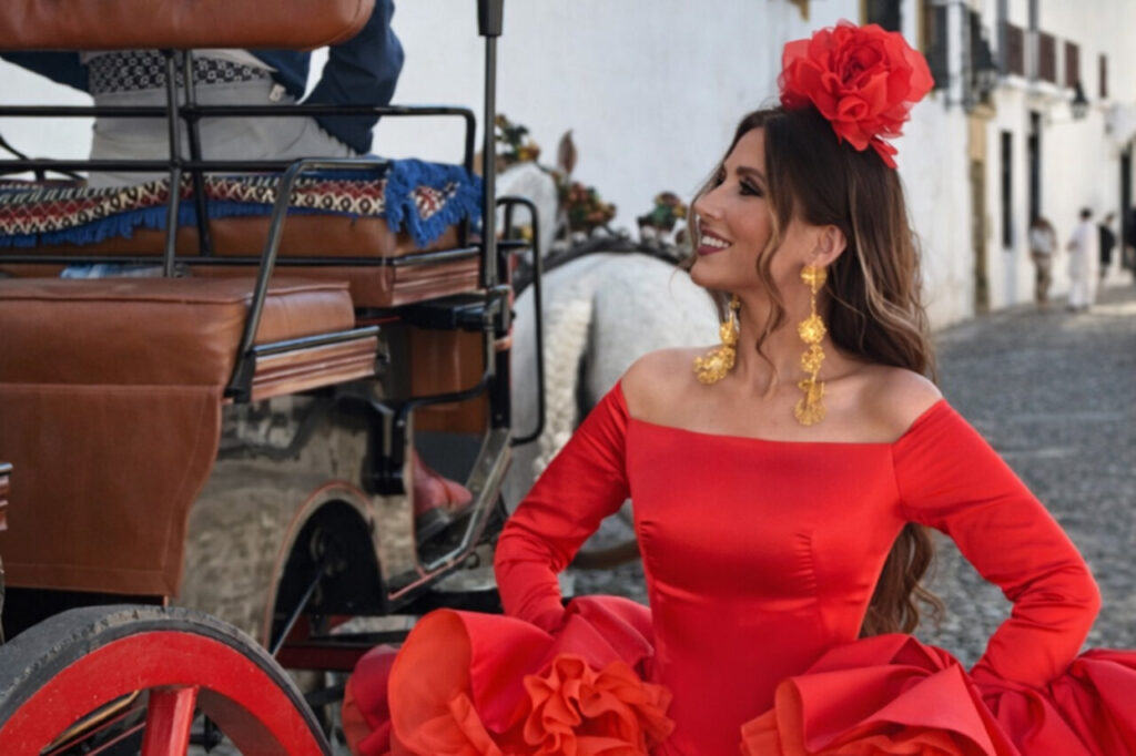 Mujer con vestido rojo y flores en el cabello junto a un carro rojo