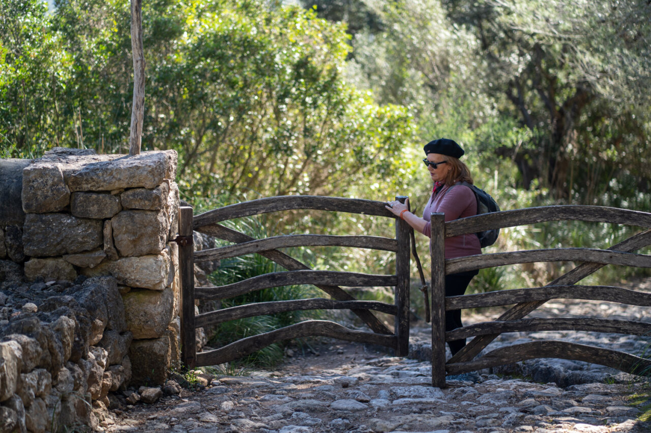 Mujer en un camino rural con puerta de madera en Mallorca.
