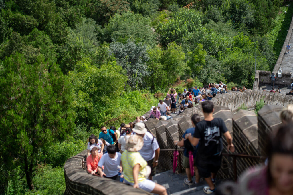 Visitantes ascendiendo por la Gran Muralla China rodeados de vegetación