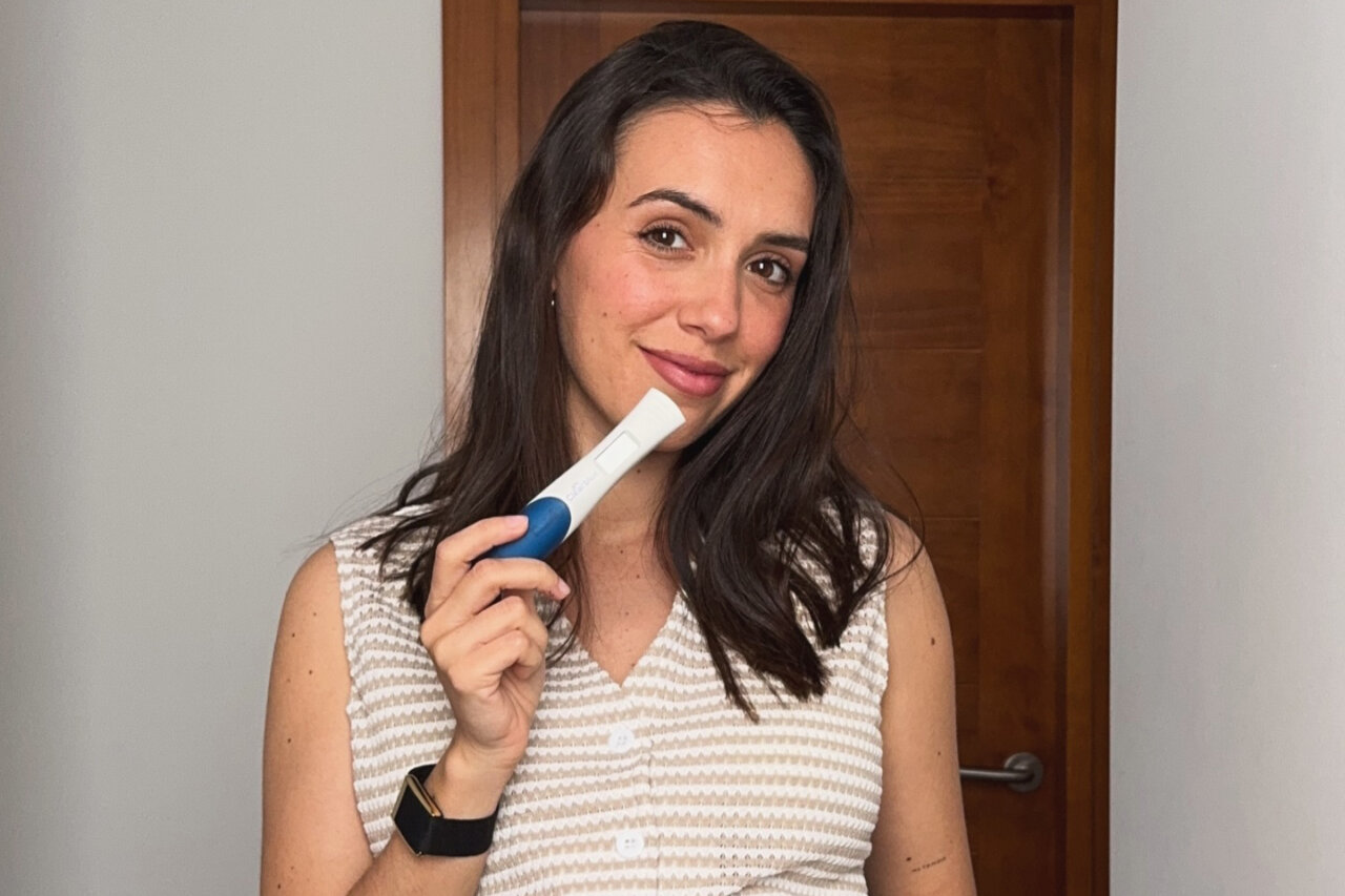 Rebeca Toribio sonríe mientras sostiene un test de embarazo positivo