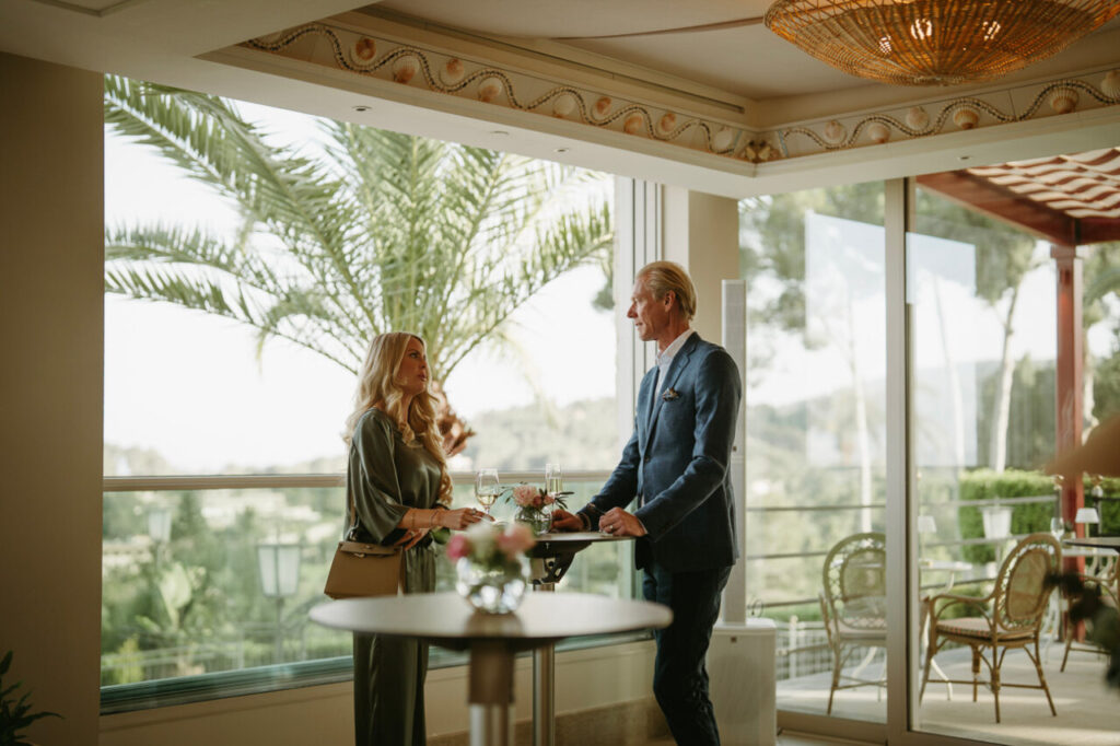 Pareja conversando en un elegante restaurante con vistas al jardín.