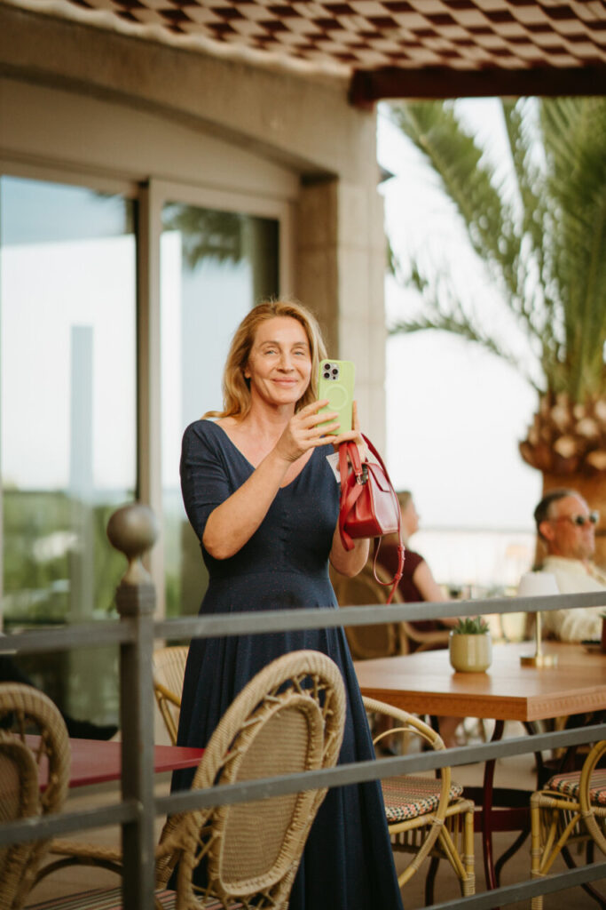 Mujer sonriente con vestido azul y teléfono en mano en un restaurante