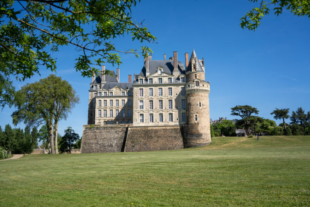 Vista del castillo de Brissac rodeado de un amplio jardín verde.