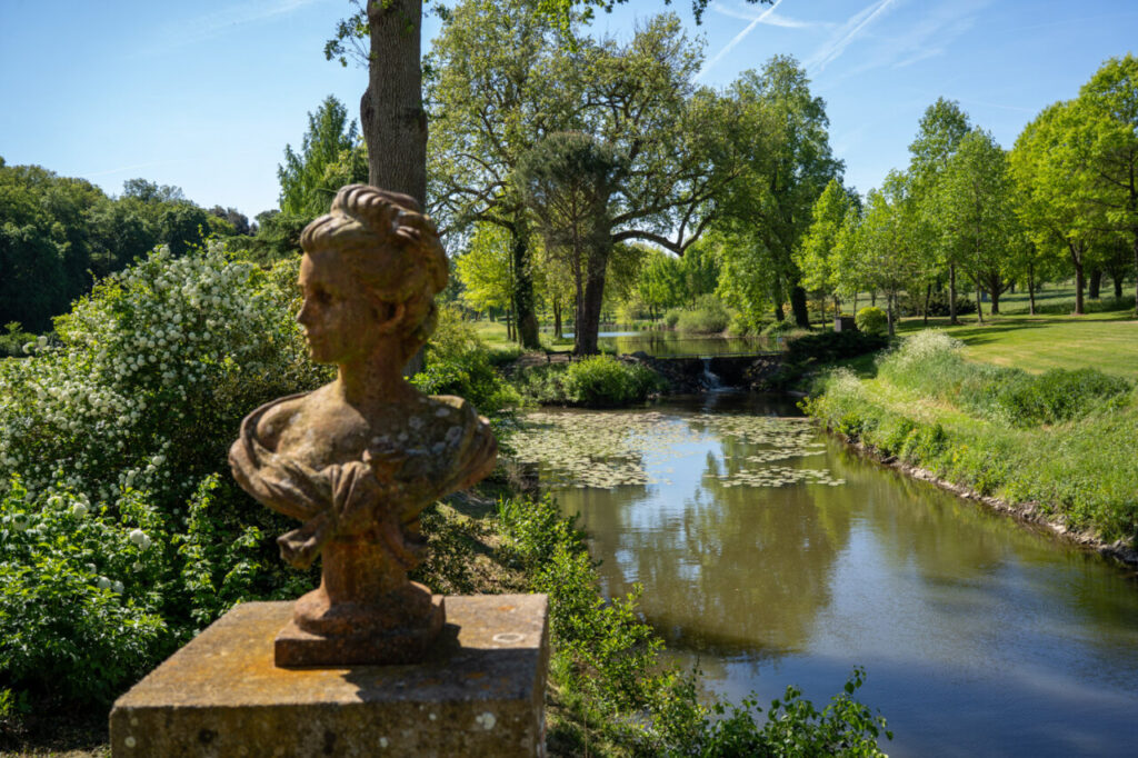 Busto en el jardín del castillo de Brissac con un río al fondo