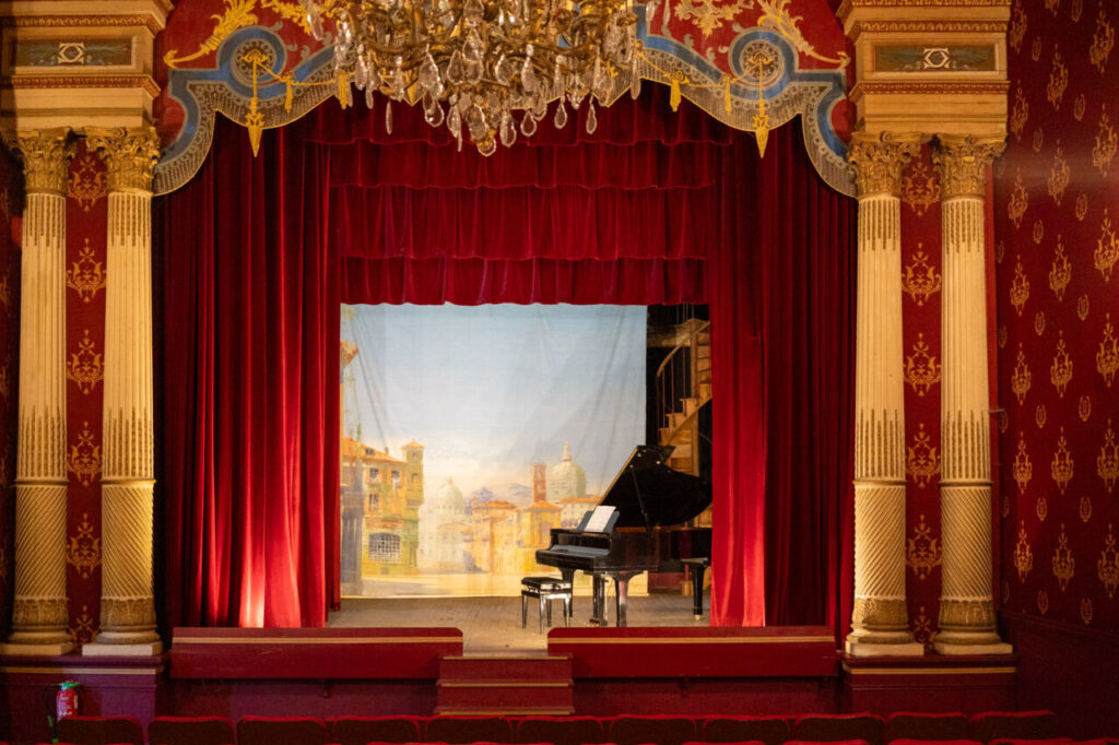 Teatro privado en el castillo de Brissac con piano y cortinas rojas