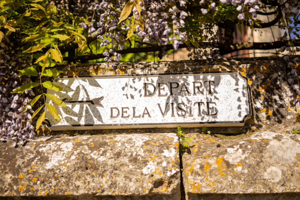 Señal de inicio de visita en el castillo de Brissac con flores alrededor