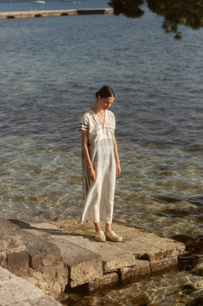 Modelo de pie junto al agua con vestido y zapatos artesanales