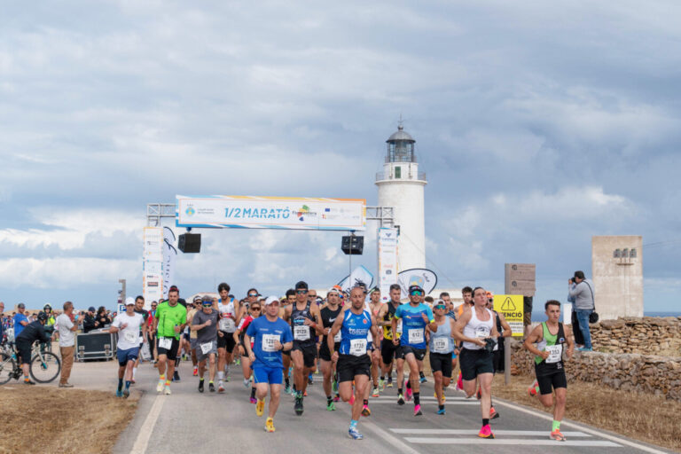 Corredores en la salida de la media maratón junto a un faro