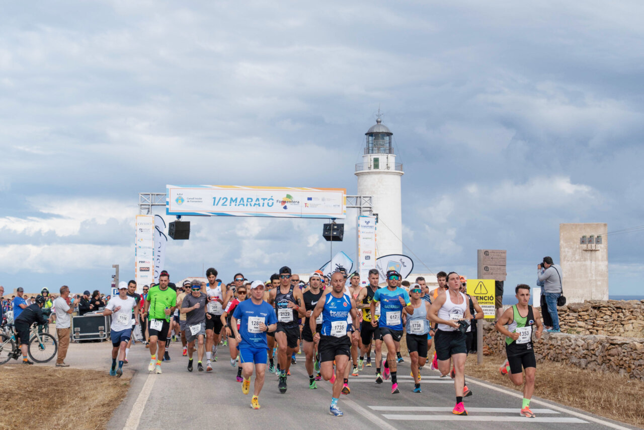 Corredores en la salida de la media maratón junto a un faro