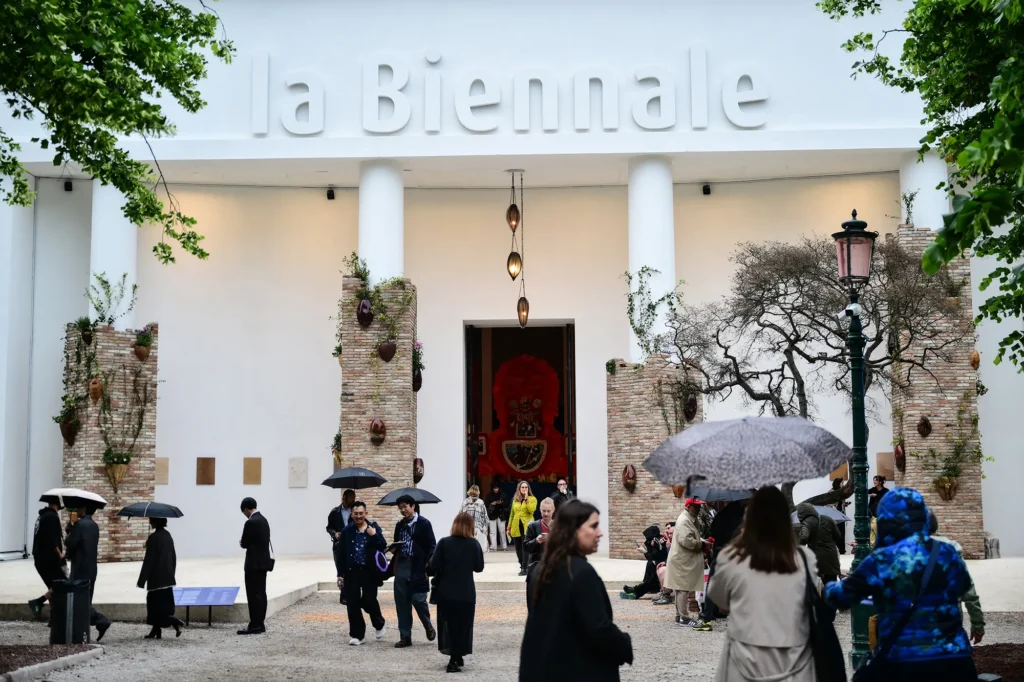 Entrada de la Bienal de Venecia con visitantes bajo paraguas