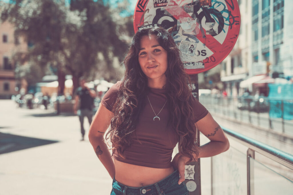 Belén Pacífico (Belucha), nominada en los MEM Awards: “El amor y el respeto por la música siguen siendo mi brújula” 1 Mujer con cabello largo y rizado posando en la calle