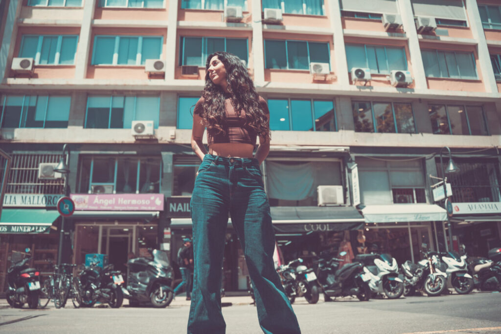 Mujer con cabello rizado posando en una calle urbana
