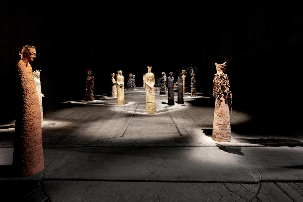Instalación artística en la Bienal de Venecia con esculturas en un pabellón oscuro