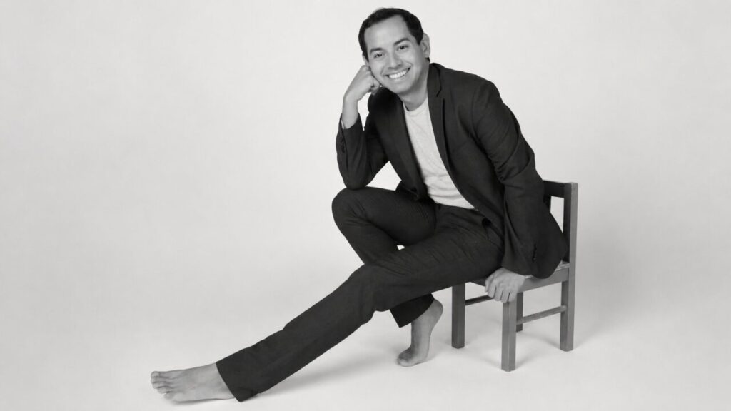 Retrato de Alex Ceball sentado en una silla con una sonrisa.