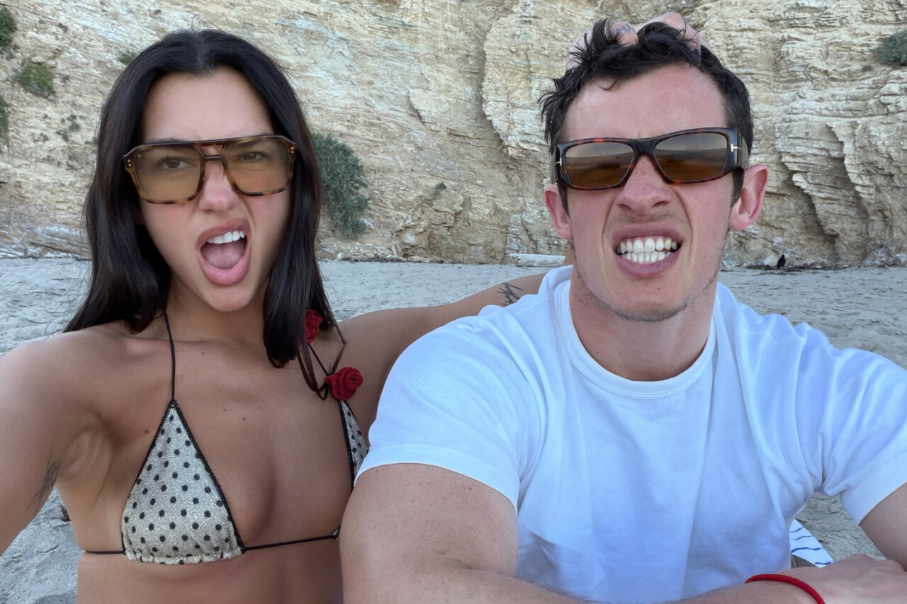 Dua Lipa y Callum Turner en la playa, haciendo caras divertidas