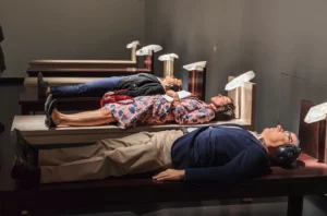 Instalación artística en la Bienal de Venecia con personas recostadas