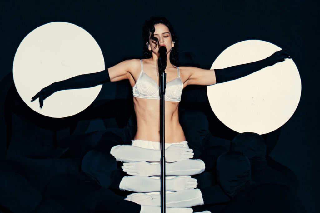 Rosalía actuando en un escenario con luces y vestuario llamativo
