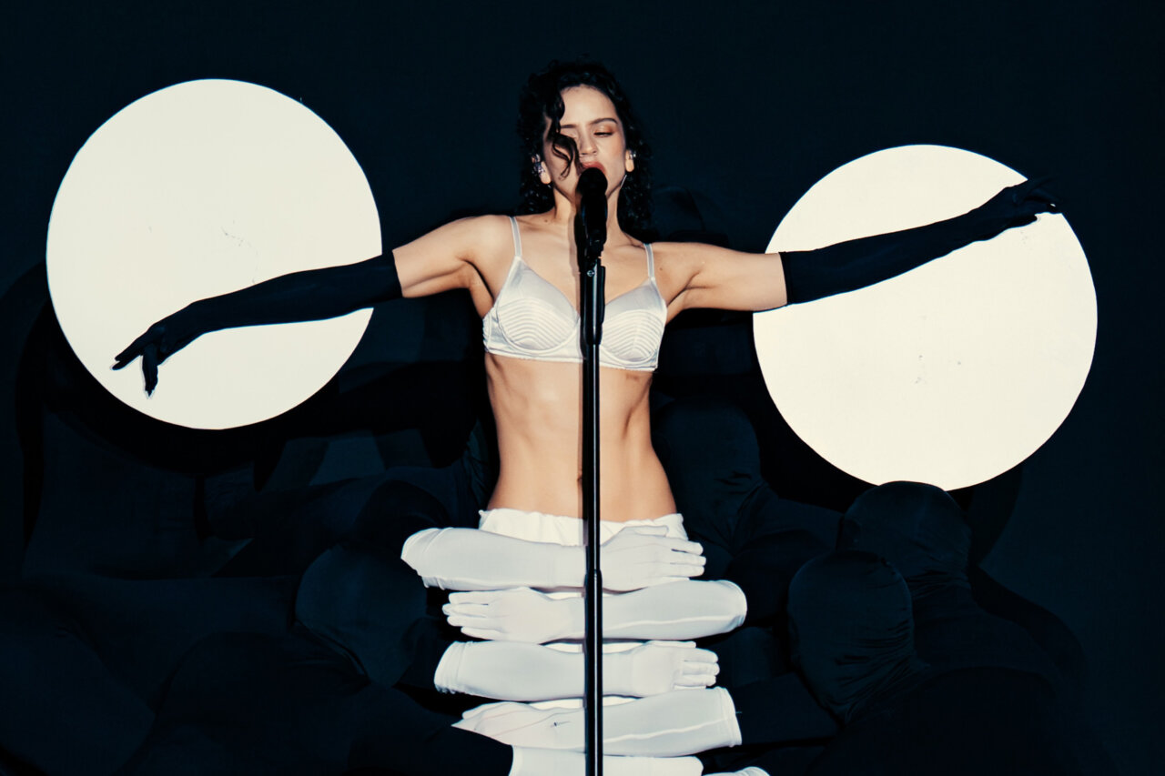 Rosalía actuando en un escenario con luces y vestuario llamativo