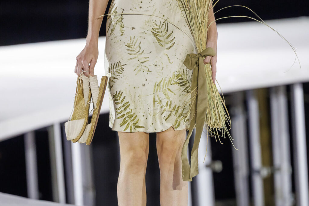 Pasarela Adlib Ibiza celebra su 55 aniversario reivindicando la libertad, la artesanía y el alma mediterránea de la isla 8 Modelo en pasarela con vestido de estampado mediterráneo y sandalias.