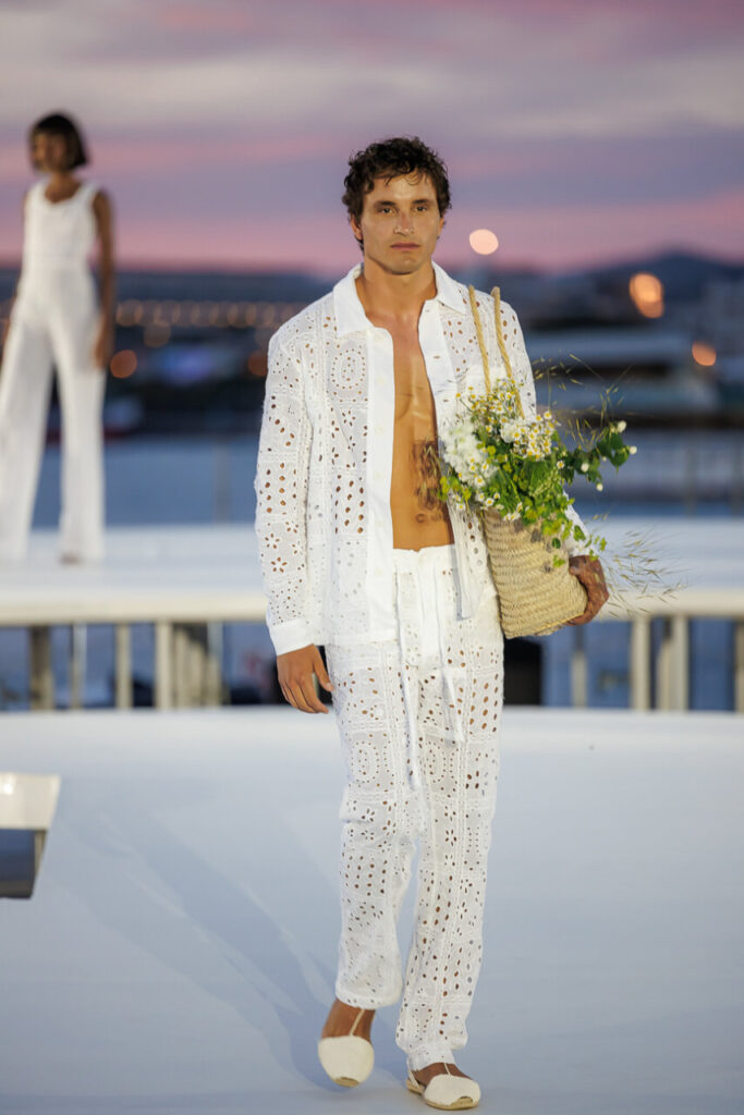 Pasarela Adlib Ibiza celebra su 55 aniversario reivindicando la libertad, la artesanía y el alma mediterránea de la isla 18 Modelo masculino en pasarela con atuendo blanco y flores