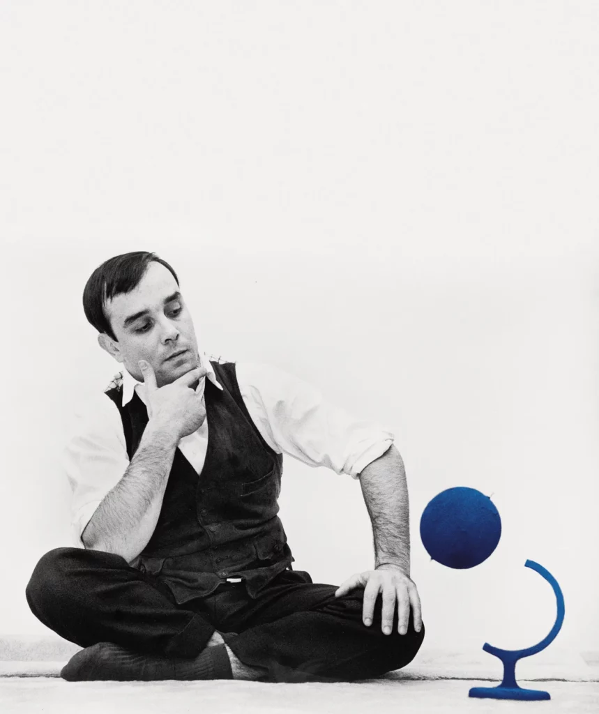 Yves Klein sentado con una escultura azul en un ambiente artístico