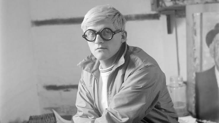 Retrato en blanco y negro de un joven artista con gafas grandes.