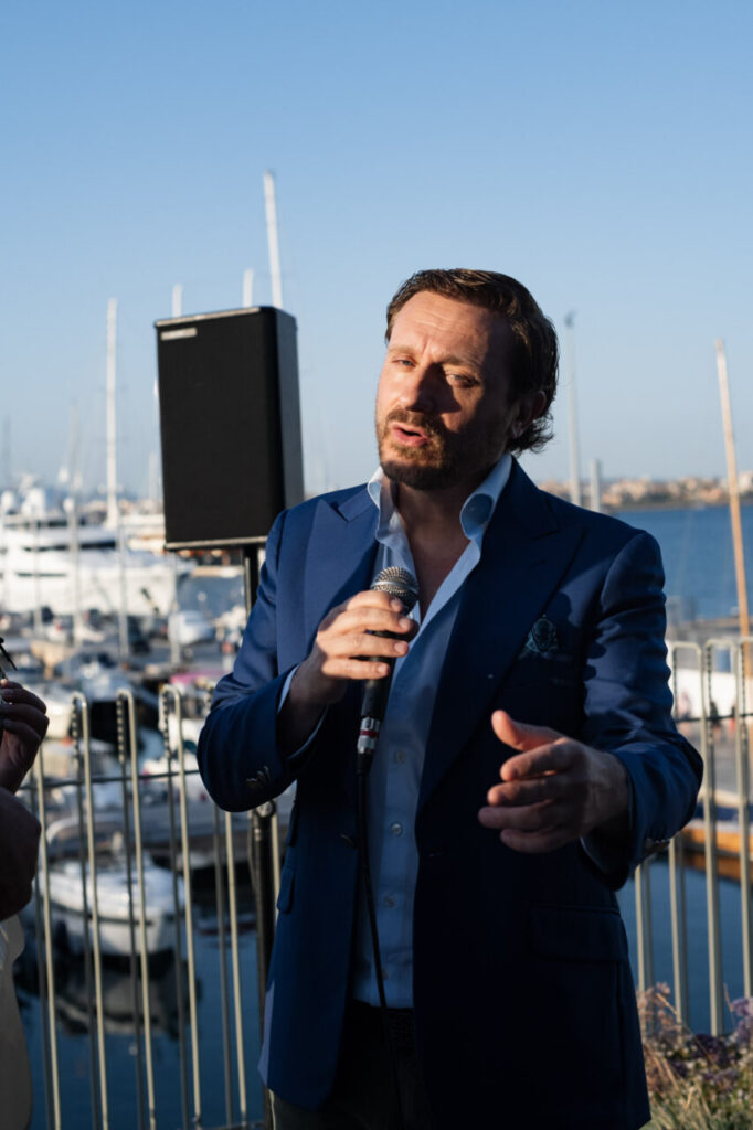 Cuando la moda se sentó frente al mar 18 Hombre hablando con micrófono en evento de inauguración al aire libre