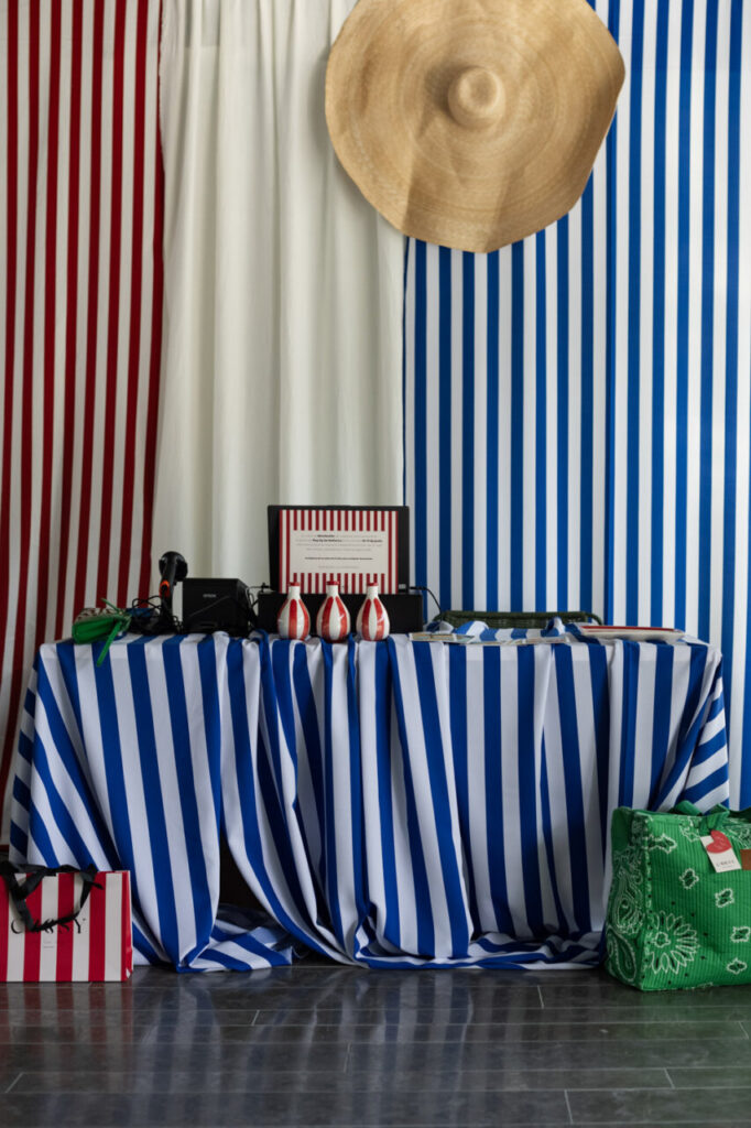 Cuando la moda se sentó frente al mar 1 Mesa decorada con manteles a rayas y sombrero en un evento de arte y diseño.