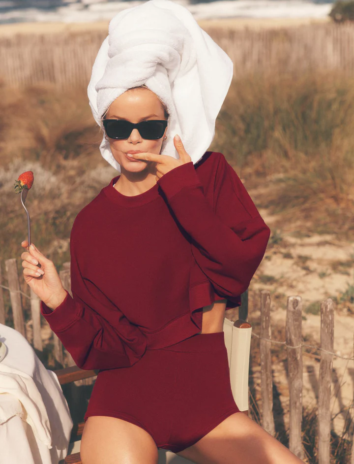 Las marcas de ropa deportiva nacidas en TikTok que están comiendo el mercado a los gigantes del sector 8 Mujer con ropa deportiva de Alo Yoga en la playa, sosteniendo una fresa.