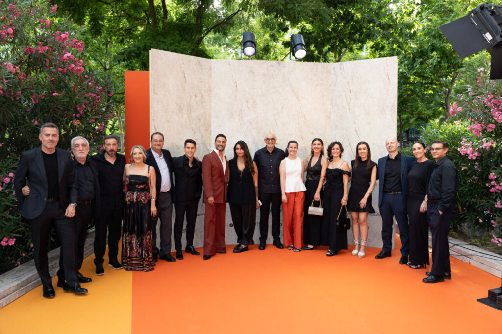Grupo de personas en evento de diseño con fondo terracota y flores