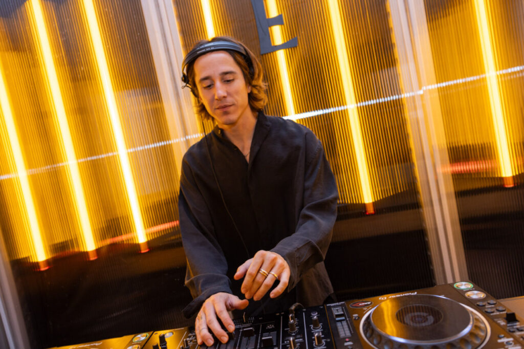 DJ actuando en evento de diseño con luces amarillas de fondo