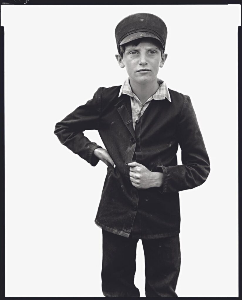 Retrato de un niño con gorra y chaqueta oscura en fondo blanco.
