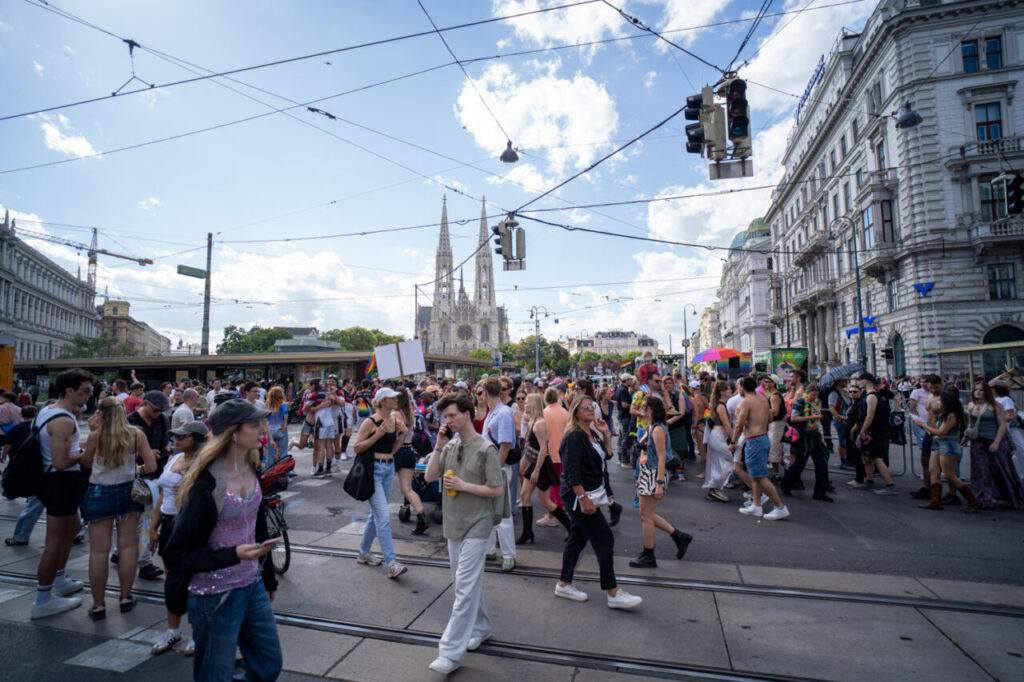 Multitud participando en la marcha del Orgullo en Viena con banderas de colores