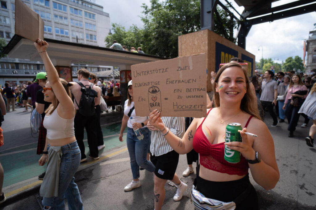 Participante sonriente en la marcha del Orgullo en Viena con un cartel