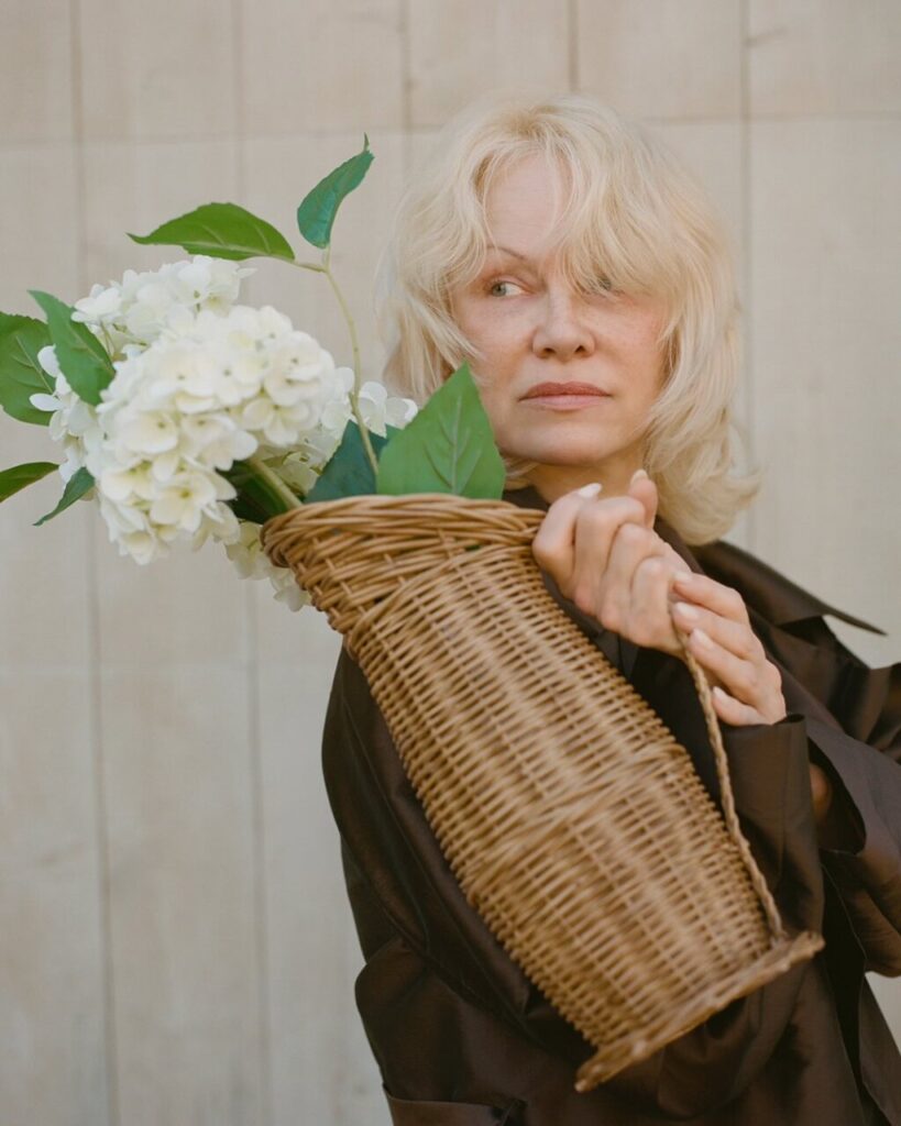 Mujer sosteniendo una cesta con flores blancas y hojas verdes