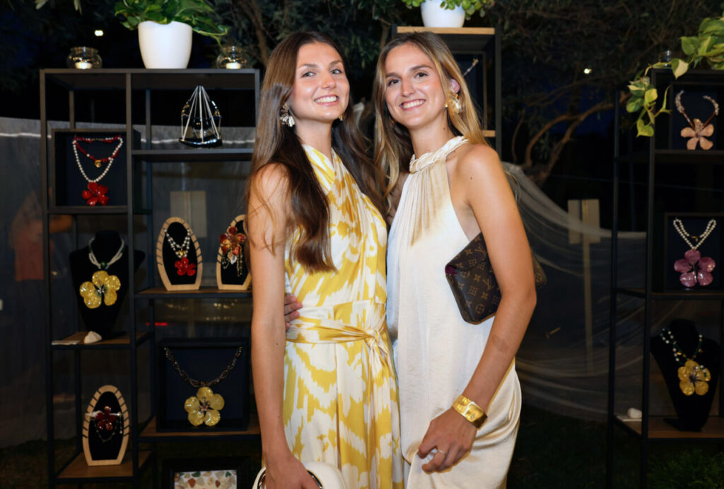 Dos modelos posando en el evento de graduación THALIBIS con joyería de fondo.