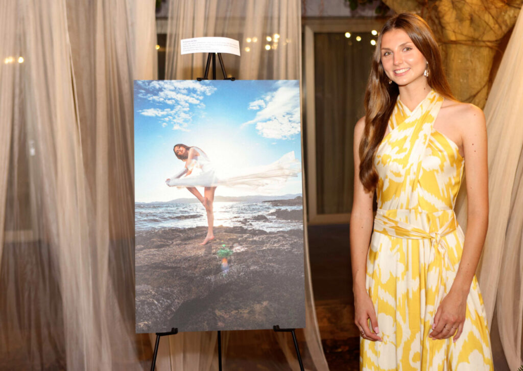 Modelo en vestido amarillo junto a una fotografía en un evento de graduación.